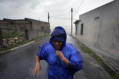 A woman covers herself with a plastic poncho while walking in heavy rains in Sabancuy, Mexico in the Yucatan peninsula on Tuesday, as Hurricane Dean passes. THE ASSOCIATED PRESS, GREGORY BULL
