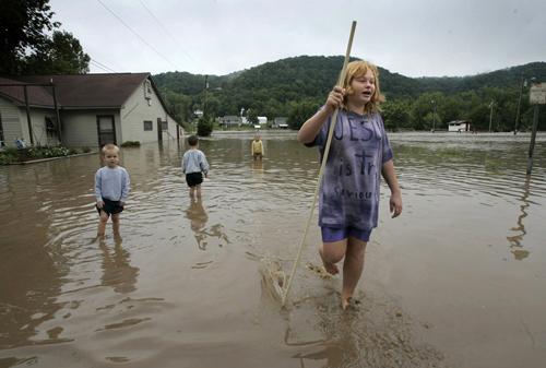 Emily Wallyung, 11, of Wauzeka, right, wades through flooded streets after floodwaters crested along the Kickapoo River in Gays Mills, Wis., on Monday. The violent system of storms has moved on to Ohio. Erica Magda
