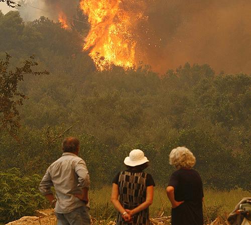 Civilians watch the fire in the Village of Paleo Varvasena about 18 kilometers south of ancient Olympia and 206 miles south of Athens on Sunday. Fires tore through parched forests and swallowed villages across Greece. THE ASSOCIATED PRESS, PETROS GIANNAKOURIS
