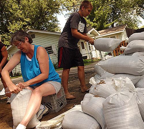 Linda King, of Antioch, Ill., ties up sandbags while Robert Harnack stacks them as water rises from the Fox River on Forest Lane in Antioch Township, Ill., on Thursday. THE ASSOCIATED PRESS, ANDRE J. JACKSON
