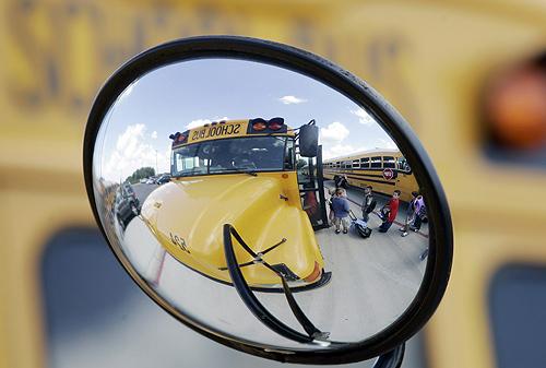 Students are reflected in a mirror as they board school buses at Fisher Elementary following the first day of classes in San Antonio on Aug. 27. A national debate is churning over whether seat belts, a decades-old vehicle safety feature, should be requir THE ASSOCIATED PRESS, ERIC GAY
