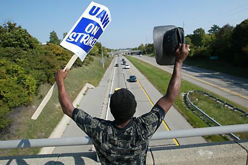 Striking United Auto Workers member Larry Miller waves from a bridge over an interstate highway to cars passing below near the General Motors Corp. Lansing Grand River assembly plant, Monday in Lansing, Mich. Thousands of United Auto Workers walked off th THE ASSOCIATED PRESS, AL GOLDIS
