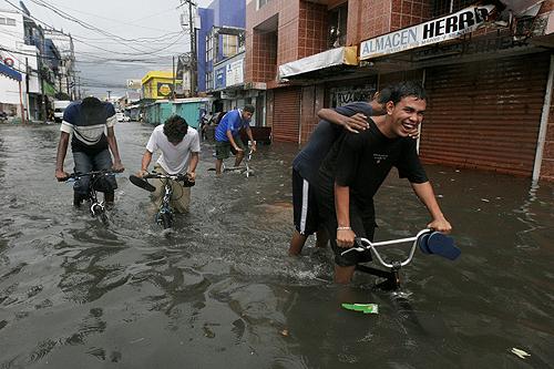 Residents ride bikes through a flooded street near a market in La Ceiba, eastern Honduras on Tuesday. THE ASSOCIATED PRESS, ESTEBAN FELIX
