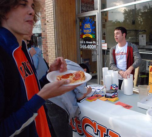 Dan Glazer (right) and Justin Gorrell (center), creators of the Web site EatCU.com, hand out free pizza outside of One World Pizza on Tuesday. Erica Magda
