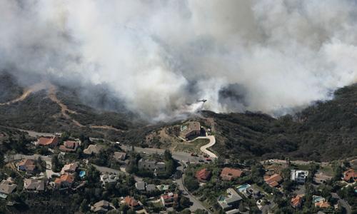 A firefighting helicopter makes a water drop over Malibu, Calif, on Monday. About 1,500 people were evacuated Monday. THE ASSOCIATED PRESS, CHRIS CARLSON
