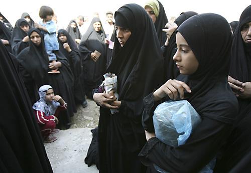 Iraqi women and their children queue to receive aid, distributed by the al- Sadr office in Shula neighborhood, northwestern Baghdad, Iraq, Monday. The al-Sadr office donated food to victims of sectarian violence. THE ASSOCIATED PRESS, HADI MIZBAN
