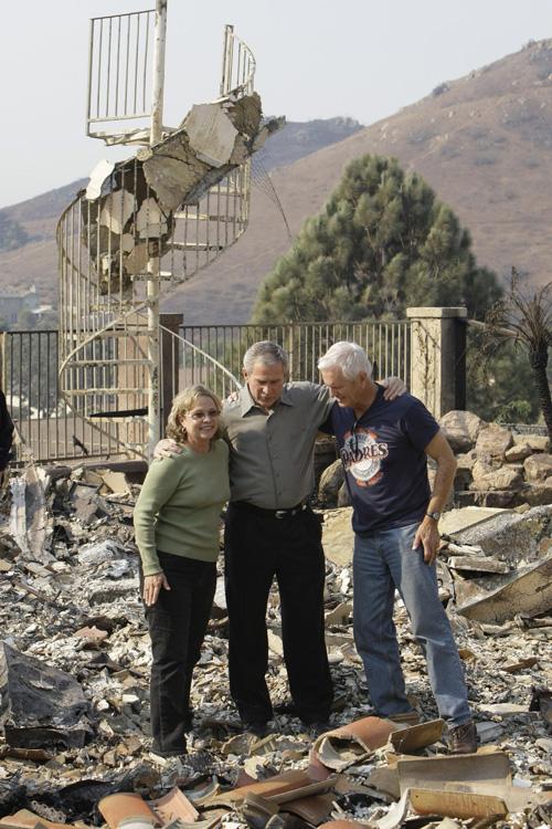 President Bush, center, hugs Kendra Jeffcoat, left, and her husband Jay, right, while walking through the remains of their home Thursday. Erica Magda
