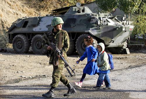 Schoolchildren walk past an armored military vehicle and a patrolling Turkish soldier on the Turkish-Iraqi border on Monday. THE ASSOCIATED PRESS, IBRAHIM USTA
