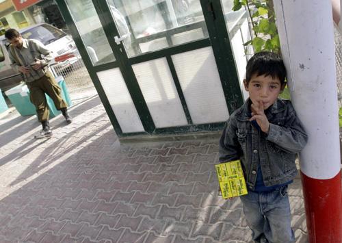 Javed, an Afghan boy, waits for customers to sell candies as an Afghan private security man stands guard outside a shopping mall in Kabul, Afghanistan Thursday. THE ASSOCIATED PRESS, RAFIQ MAQBOOL
