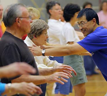 Weimo Zhu, associate professor in kinesiology and community health, corrects participants in a qigong exercise on Thursday night at Freer Hall. Zhu led a workshop of healthy living through qigong over the weekend. Laura Prusik
