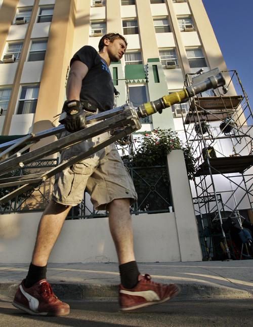 A set worker carries a light stand as lights on scaffolding shine into rooms during the production of an Internet feature on a location shoot in Los Angeles on Wednesday. Writers, producers and a federal mediator continued talking Wednesday with the hope Reed Saxon, The Associated Press
