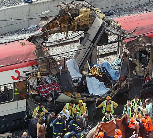 Rescue workers cover up bodies alongside a bomb-damaged passenger train, following a number of explosions in Madrid, Spain, on March 14, 2004. Erica Magda
