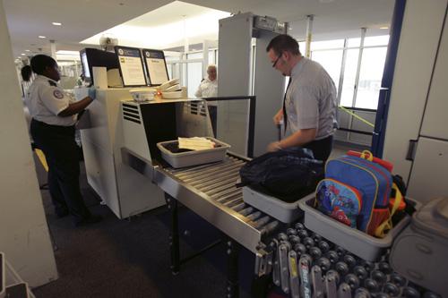 Shanyea Foster, a Transportation Security Administration screener, checks carry-on luggage as an airline passanger loads his baggage at a security check point at Newark Liberty International Airport in New Jersey, Thursday. Mike Derer, The Associated Press
