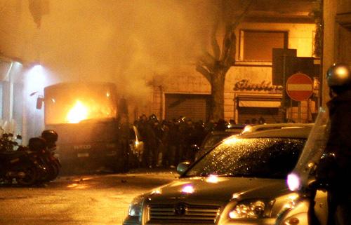 Policemen stand next to a burning police bus in downtown Rome on Sunday following clashes between Lazio team soccer fans and policemen. A police officer accidentally shot and killed a Lazio soccer fan Sunday while trying to quell a clash with Juventus sup Laura Prusik
