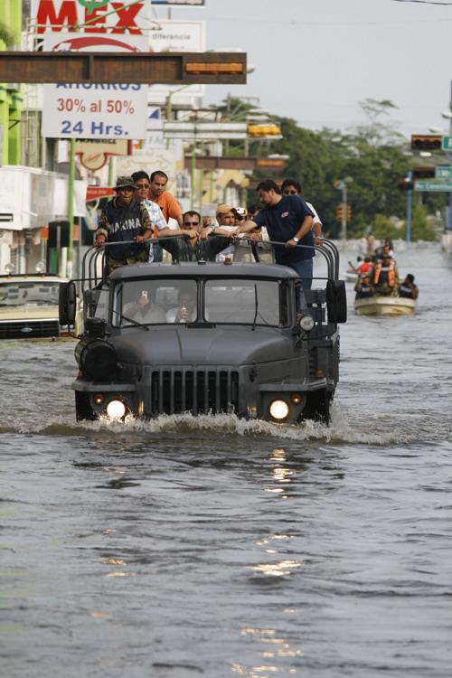 Residents are transported on a Navy truck through a flooded street in Villahermosa, eastern Mexico, Monday. At least 20,000 people were still trapped Monday on the rooftops of homes swallowed by water. Erica Magda
