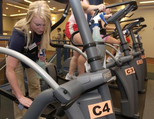 Brittany Jansen, Freshman in AHS, cleans an elliptical machine in the CRCE Fitness Area on Thursday afternoon, Nov. 1, 2007. The staff watches in particular in their cleaning duties to get areas of the machine other than the handlebars, which are often th Erica Magda
