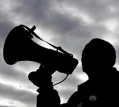 Willie English, a Service Employees International Union Local 73 representative, yells through a megaphone outside the University of Illinois-Springfield Public Affairs Center, Wednesday. Erica Magda
