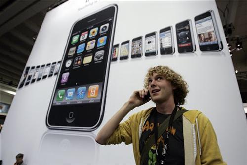 Attendee Wil Gieseler talks on his Apple iPhone in front of a iPhone poster at the MacWorld Conference in San Francisco on Tuesday. Paul Sakuma, The Associated Press
