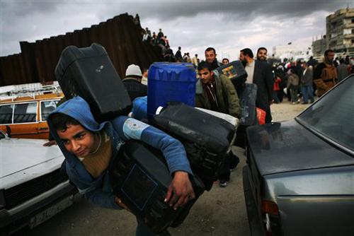 Palestinians carry empty canisters for fuel as they cross a destroyed section of the border wall from Rafah, in the southern Gaza Strip, to Egypt Wednesday, Jan. 23, 2008. Masked Palestinian gunmen blew holes into the Gaza-Egypt border wall Wednesday, and Kevin Frayer, The Associated Press
