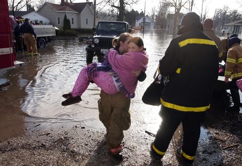 Watseka firefighter Kyann Siebring carries Alisha Condon to safety after Alisha and both her parents were evacuated from their home Wednesday morning. The Associated Press
