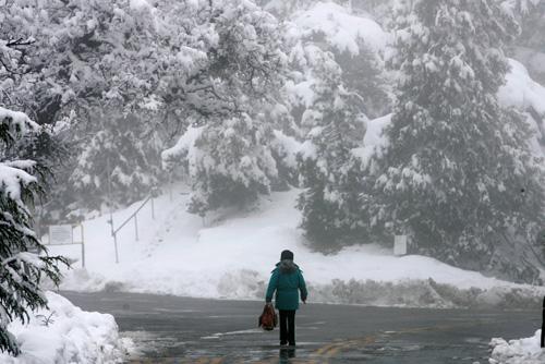 A woman walks along a road Wednesday at the Lick Observatory on Mt. Hamilton in San Jose, Calif. The area received nearly a foot of snow. Marcio Jose Sanchez
