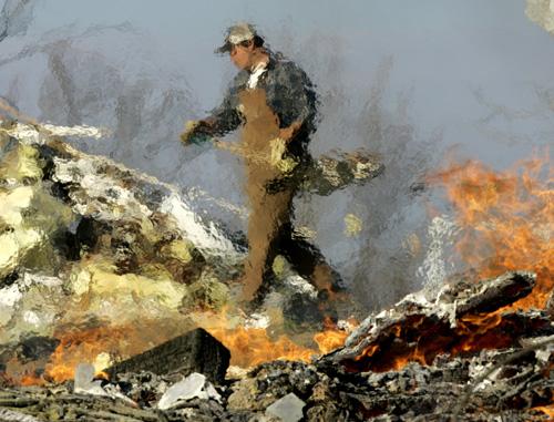 Church member Bobby Sircy is distorted by heat vapors as he carries a shovel of debris past a burn pile at the destroyed Antioch Missionary Baptist Church near Layfayette, Tenn. on Friday. The 120-year-old building was destroyed when a series of tornadoes Charlie Riedel, The Associated Press
