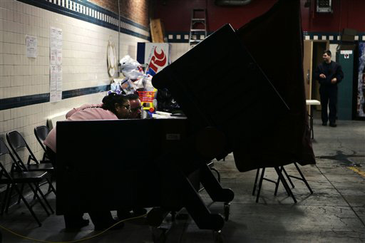 Poll worker Yvonne Irizarry, left, and a fellow poll worker look at the back of a voting machine that was not working at a polling place at a fire house in Hoboken, N.J., Tuesday, Feb. 5, 2008. The voting machine started working about 45 minutes after the Mike Derer, The Associated Press
