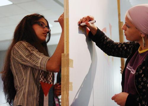 Samiyah Nageeb junior in LAS, left, and Nada Youssef, freshman at Parkland, right, express their emotions on a wall representing the border wall being constructed by the Israelis on Palestinian land during Cafe Intifada at Allen Hall on Thursday, April 3, Jeremy Berg

