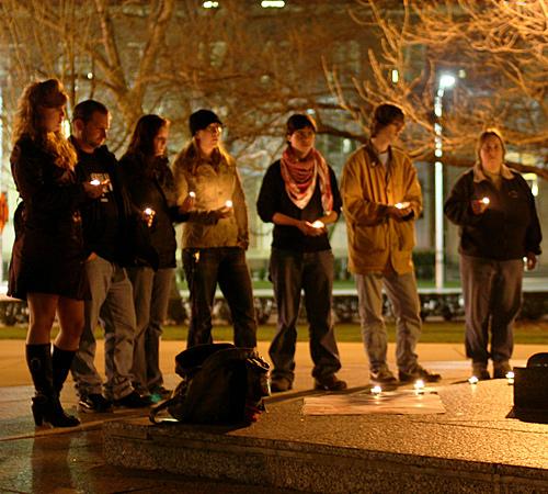 People stand with candles as the names of the Illinois soldiers killed in Iraq are read off at the Alma Mater statue on Friday night. The Campus Antiwar Network held a candlelight vigil to pay tribute to soldiers and civilians killed in Iraq. Log onto ww Donald Eggert
