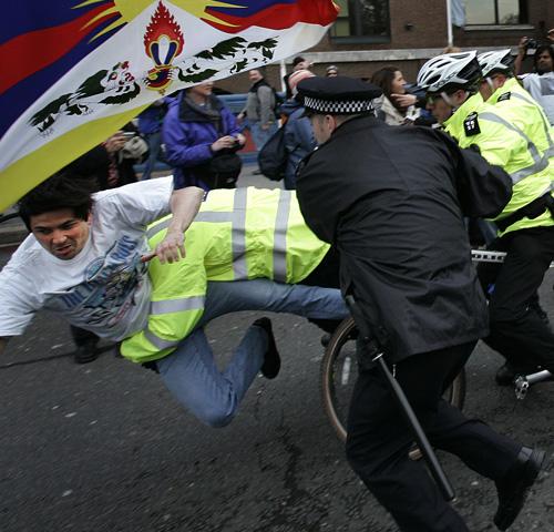 British police officers jump to apprehend an anti-China, pro-Tibet demonstrator as he tried to interrupt the Olympic torch parade over Tower Bridge on Sunday. Police scuffled with protesters as Olympians and dignitaries carried the torch during a chaotic Lefteris Pitarakis, The Associated Press
