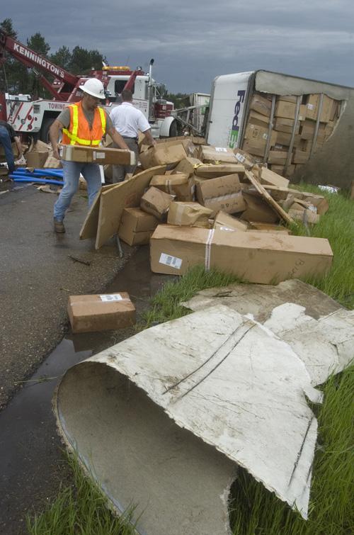 Jason Waters, who is with Texas Dept. of Traffic, from Atlanta, Texas, helps to move packages from an overturned semi-trailer on Thursday in Leary, Texas. Robb Pittard, The Associated Press
