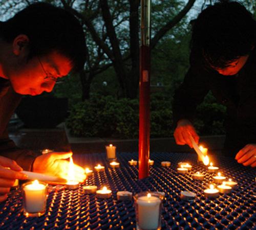 Graduate students Ming Wu, left, and Di Yun light candles at a vigil on the Quad on Thursday night in support of the people affected by the earthquake in China. The event included a moment of silence and a speech given in Chinese and English. Susan Kantor
