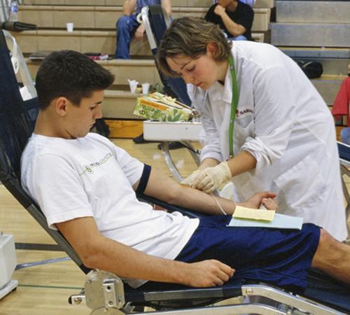 A teenager is seen giving blood during a blood drive at Saguaro High School in Scottsdale, Ariz. A study by the American Red Cross shows that complications from donating blood are rare but happen much more often in teens than in older donors. Blood Systems/United Blood Services
