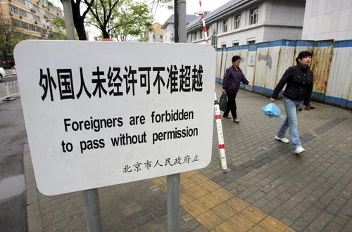 Residents walk past a sign which forbids foreigners to pass in Beijing on April 21. A document issued Monday by the Beijing organizing committee spells out guidelines for foreigners at the Olympics. Greg Baker, The Associated Press
