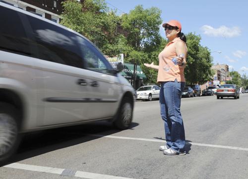 Chicago Police Officer Grace Delgado, posing as a pedestrian in an undercover operation, throws up her hands as a van whizzes by her in a crosswalk in Chicago on June 17. The van was pulled over and given a warning ticket during the operation to call moto Rich Hein, The Associated Press
