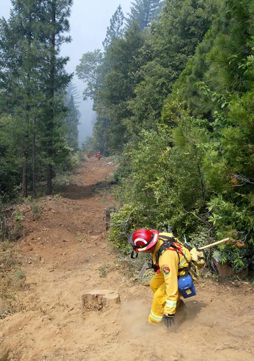 Fire Captain-Division Supervisor Todd Tindill hikes down a hill to help firefighters contain the West Fire near Stirling City, Calif., Monday. Hundreds of wildfires burned across central and northern California for a second week Monday. The Associated Press
