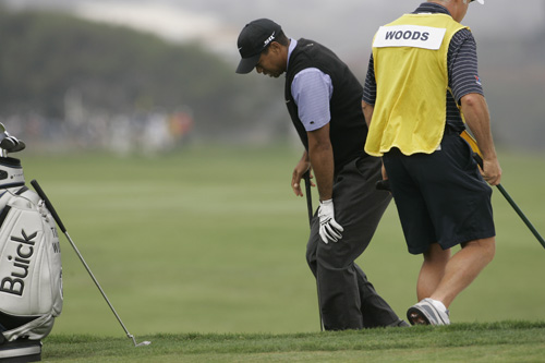 Tiger Woods holds onto his knee as he comes out of a bunker on the fourth hole during the third round of the US Open championship at Torrey Pines Golf Course in San Diego on June 14. Woods said his left knee has been sore his entire PGA Tour career and ex The Associated Press
