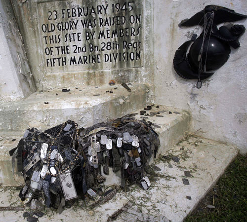A pile of American military dogtags and other military memorabilia rest on top of a monument marking the point where U.S. Marines raised the flag over Iwo Jima on top of Mount Suribachi. David Guttenfelder, The Associated Press
