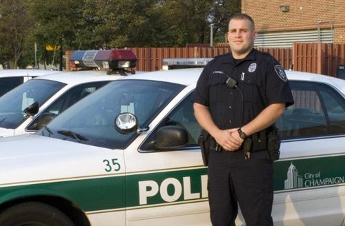 Officer Tom Petrilli of the Champaign Police Department and a member of the Community Assistance Team poses in front of a row of police cars. Trevor Greene

