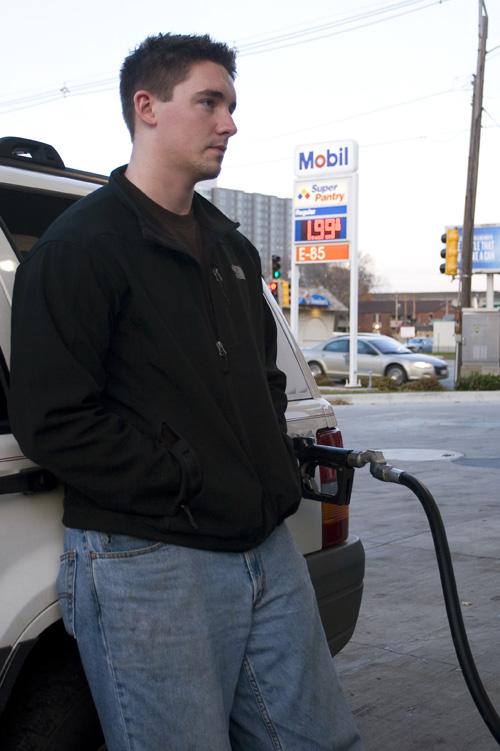 Tyler Dailey, a senior in Engineering, fills up his SUV at the Mobil gas station an First and Green streets. Dailey says he hopes low prices persist. Erica Magda
