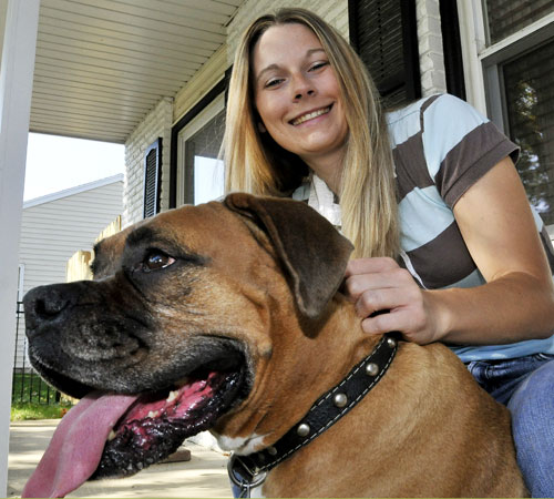 Kristen Duffy sits on the porch of her house with Porkchop, a 5-year-old American Boxer, Monday afternoon. Duffy, a 2002 graduate of the College of Business, recently opened a pet day care service out of her home. Fetch! Pet Care provides services to pets Erica Magda
