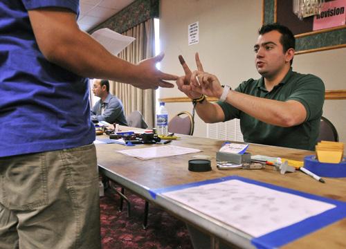 Aldo Mora-Castro, a representative from the Mexican Consulate in Chicago, shows a Mexican citizen how to position his fingers while making fingerprints on national documents Thursday at the Illinois Hotel in Urbana. Erica Magda
