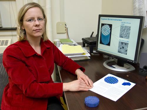Professor Amy Wagoner Johnson displays diagrams and a scale model of a synthetic bone implant she developed. The implant is only a few millimeters in diameter and replaces the scaffold in a bone, which helps it regrow. Erica Magda
