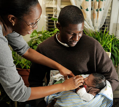 Fritz Jean, seated, and his girlfriend Renia Morant play with their 10-day-old baby, Quincy, during an interview Tuesday at his apartment in New York. Stephen Chernin, The Associated Press

