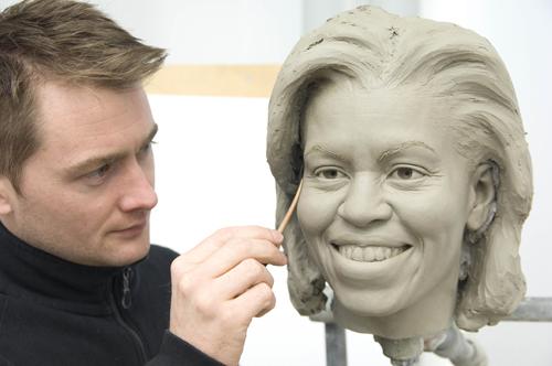 This image provided by Madame Tussauds shows senior sculptor Colin Jackson working on a clay head mold of first lady Michelle Obama at Merlin Studios in London. The Associated Press
