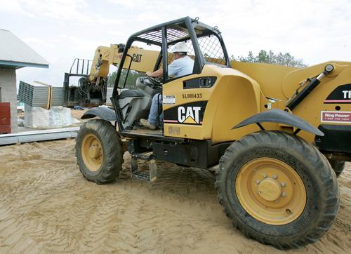 Rick Williamson uses an all-terrain Caterpillar front-end loader to move a bundle of roofing material at a construction site on Monday in Hosford, Fla. Caterpillar, following other major U.S. corporations, has announced around 20,000 job cuts. Phil Coale, The Associated Press
