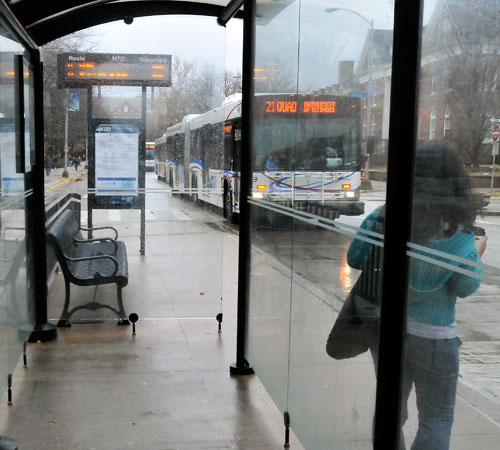 A student watches as MTD buses pull up to the Transit Plaza stop on Wright Street in Urbana on Wednesday. Erica Magda
