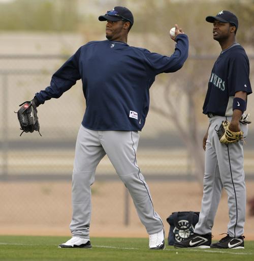 Seattle Mariners outfielder Ken Griffey Jr.. left, throws while Prentice Redman, right, looks on during spring training baseball Sunday, Feb. 22, 2009 in Peoria, Ariz. (AP Photo/Charlie Riedel)
