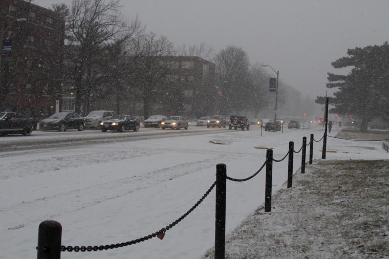 Cars drive carefully through the snow on Fourth Street as a snow storm blows through Illinois.