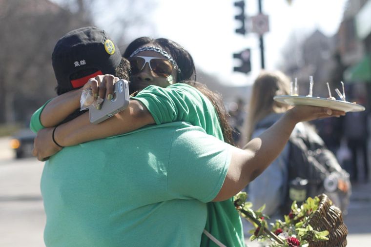 Kilani Gaston, a junior, hugs her friend Jayla Lewis at the corner of Green and Wright during Unofficial on Friday. Lewis was offering free food samples from Panda Express during the day.  